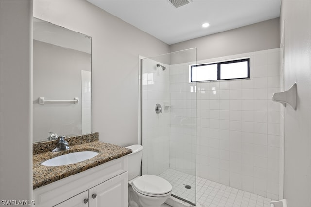 bathroom featuring tiled shower, toilet, and large vanity