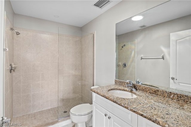 bathroom featuring vanity with extensive cabinet space, a tile shower, and toilet