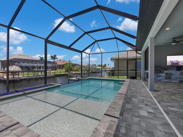 view of pool with a lanai, ceiling fan, a water view, and a patio