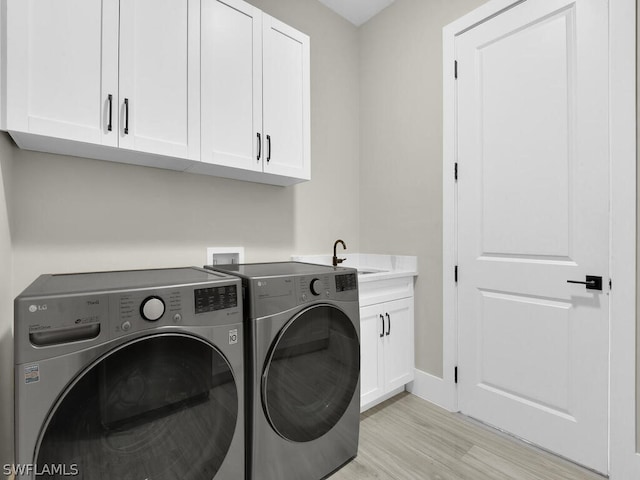 washroom with cabinets, separate washer and dryer, light hardwood / wood-style floors, and sink