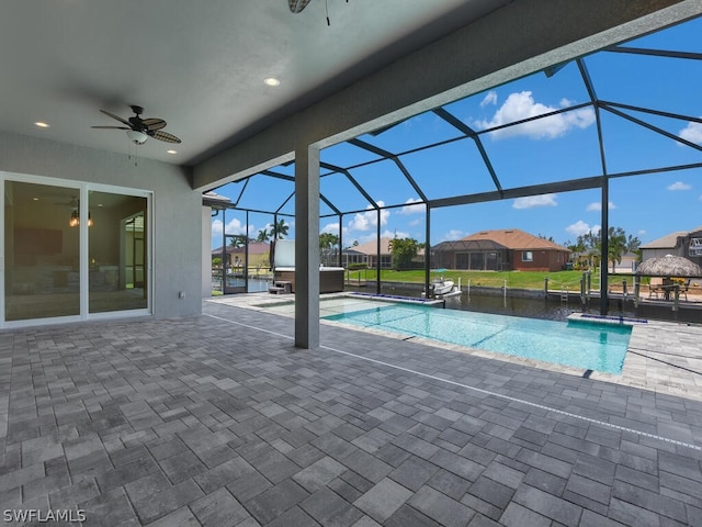 view of swimming pool with ceiling fan, a lanai, and a patio