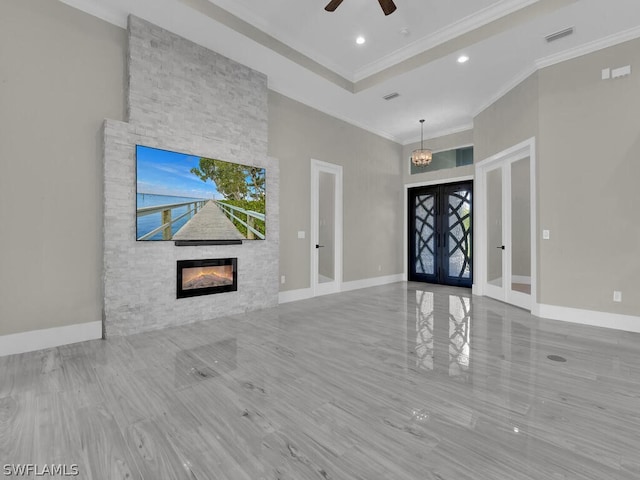 entryway with french doors, a stone fireplace, crown molding, hardwood / wood-style flooring, and ceiling fan