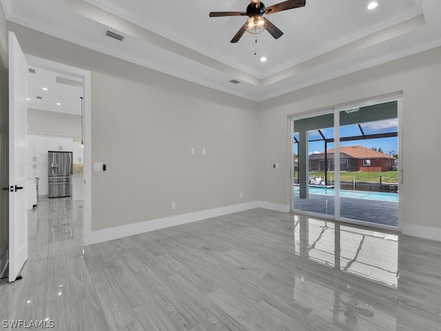 spare room with ceiling fan, light hardwood / wood-style flooring, crown molding, and a tray ceiling