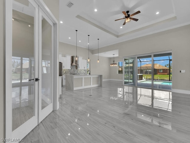 interior space with a tray ceiling, ceiling fan, crown molding, and sink