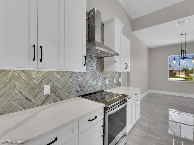 kitchen featuring stainless steel range with electric stovetop, pendant lighting, wall chimney range hood, light stone counters, and white cabinetry