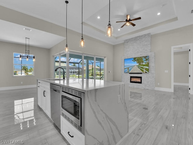 kitchen featuring white cabinetry, sink, a kitchen island with sink, a fireplace, and appliances with stainless steel finishes