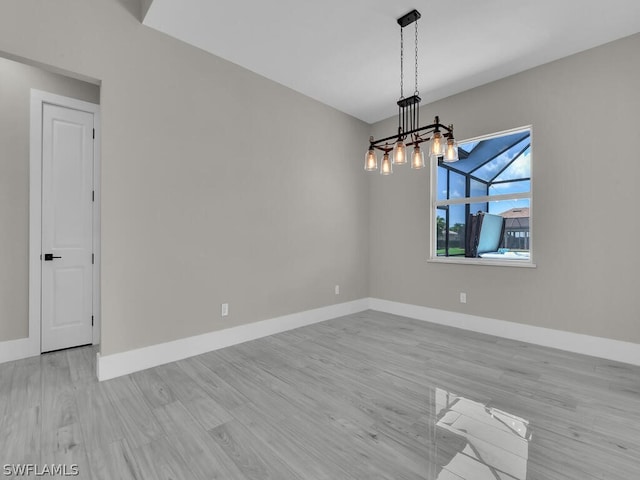 spare room with light wood-type flooring and a chandelier