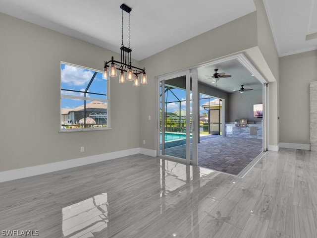 unfurnished dining area featuring ceiling fan with notable chandelier, light wood-type flooring, and ornamental molding