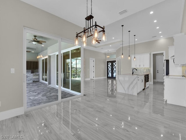 unfurnished dining area featuring ceiling fan with notable chandelier and sink