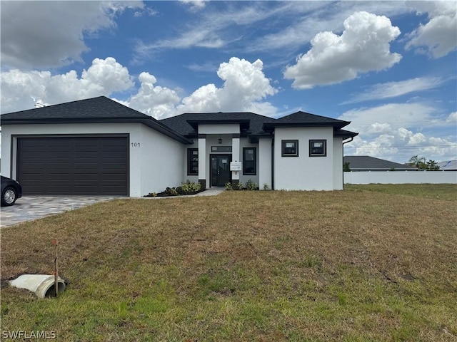 prairie-style home with a garage, a front lawn, decorative driveway, and stucco siding