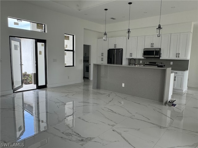 kitchen featuring decorative light fixtures, black fridge, a towering ceiling, and light tile floors