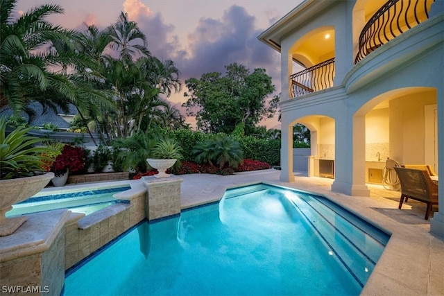 pool at dusk featuring a patio area