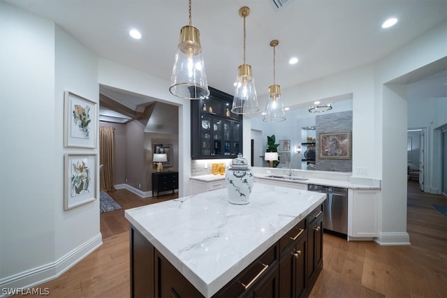 kitchen featuring hanging light fixtures, dishwasher, wood-type flooring, sink, and a center island