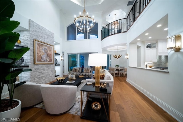 living room featuring a towering ceiling, a notable chandelier, and light wood-type flooring