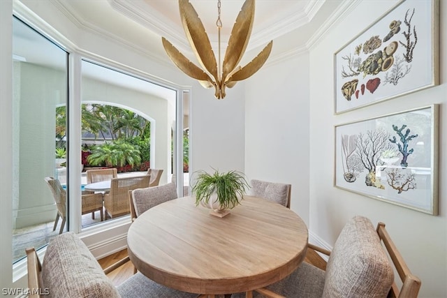 dining space with ornamental molding, wood-type flooring, and a raised ceiling