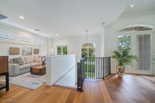 living room featuring light hardwood / wood-style flooring, crown molding, and an inviting chandelier