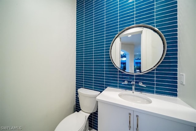 bathroom with tile walls, backsplash, vanity, and toilet