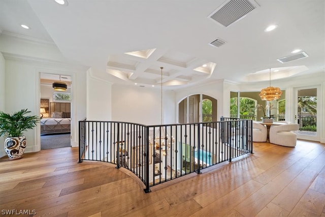 hallway with light hardwood / wood-style floors, crown molding, coffered ceiling, beamed ceiling, and an inviting chandelier