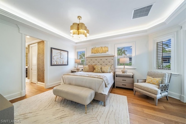 bedroom with a chandelier, crown molding, wood-type flooring, and a raised ceiling