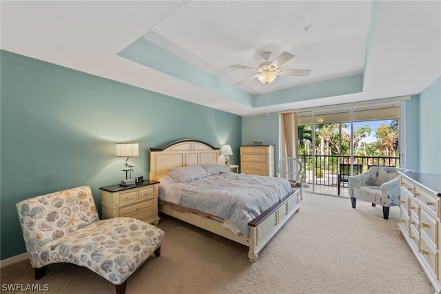 carpeted bedroom with ceiling fan, a raised ceiling, and access to outside