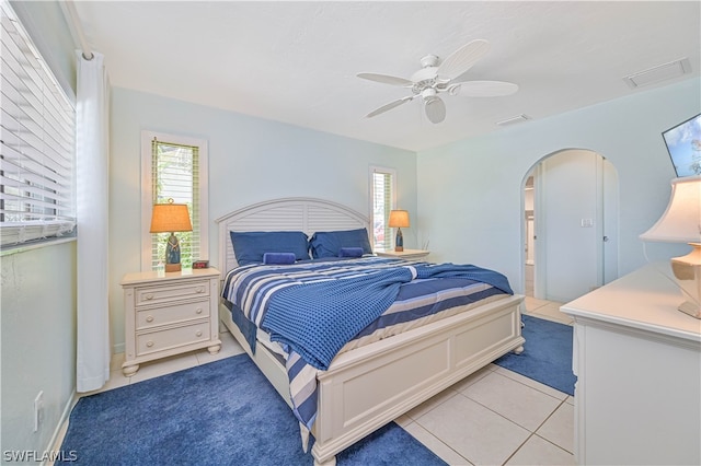 bedroom with ceiling fan, light tile patterned flooring, and ensuite bathroom