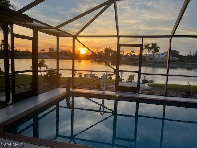 pool at dusk with a lanai and a water view