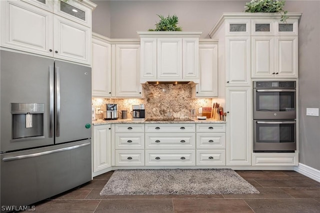 kitchen featuring decorative backsplash, light stone countertops, white cabinets, and appliances with stainless steel finishes