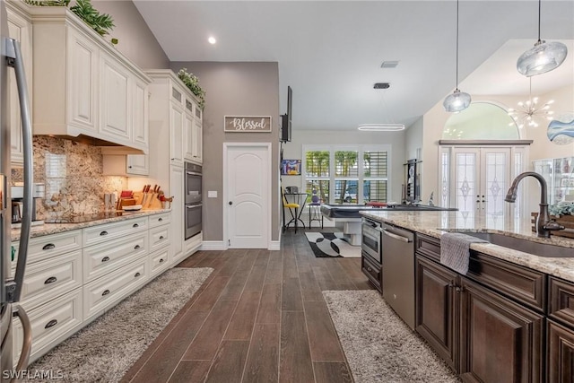 kitchen featuring appliances with stainless steel finishes, dark brown cabinetry, dark wood-type flooring, sink, and decorative light fixtures