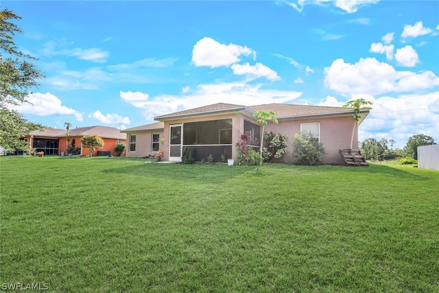 rear view of house with a sunroom and a lawn