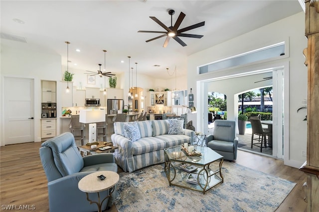 living room featuring a towering ceiling, ceiling fan, and hardwood / wood-style floors