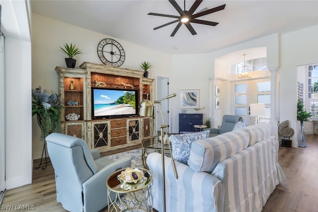 living room with ceiling fan with notable chandelier, hardwood / wood-style flooring, and decorative columns