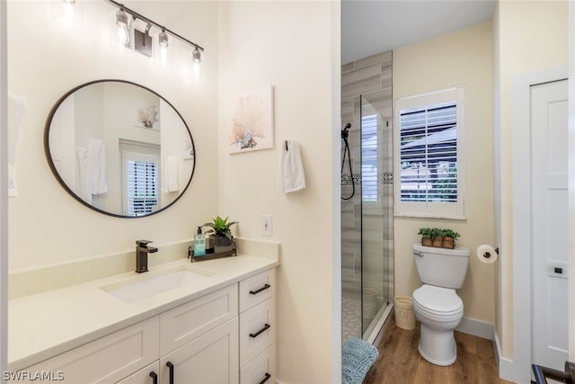 bathroom featuring vanity with extensive cabinet space, hardwood / wood-style floors, toilet, and a shower with shower door