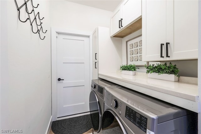 laundry area with separate washer and dryer and cabinets