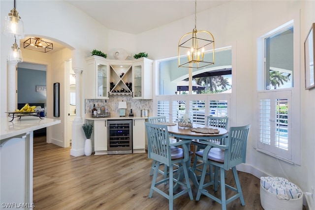 dining space with wine cooler, light hardwood / wood-style flooring, and a notable chandelier