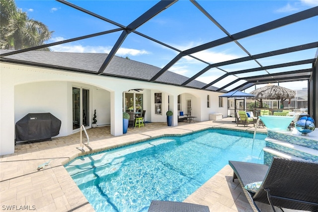 view of pool featuring ceiling fan, glass enclosure, a patio area, and area for grilling