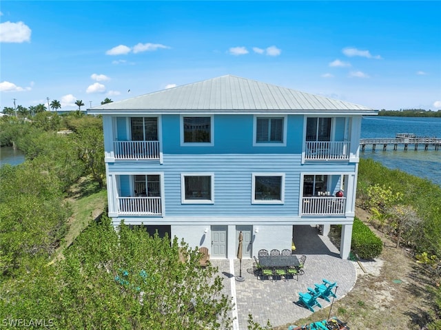 back of property with a patio area, a balcony, and a water view