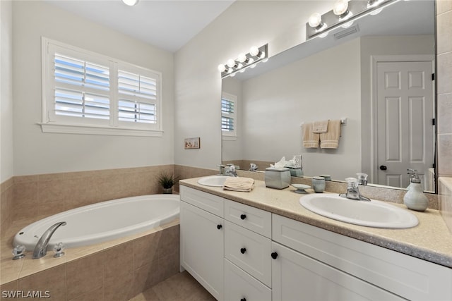 bathroom with tile flooring, tiled tub, oversized vanity, and double sink