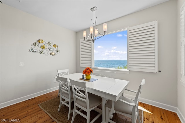 dining area with hardwood / wood-style flooring, a water view, and a chandelier