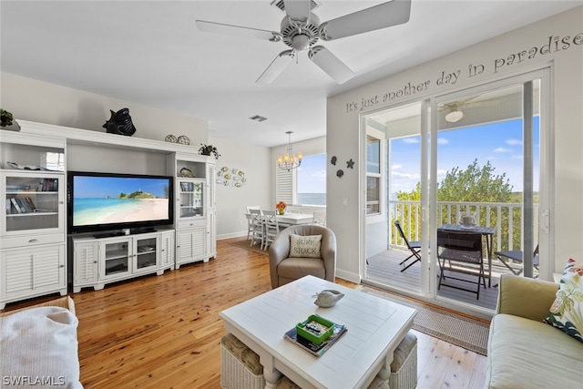 living room featuring light hardwood / wood-style floors and ceiling fan with notable chandelier