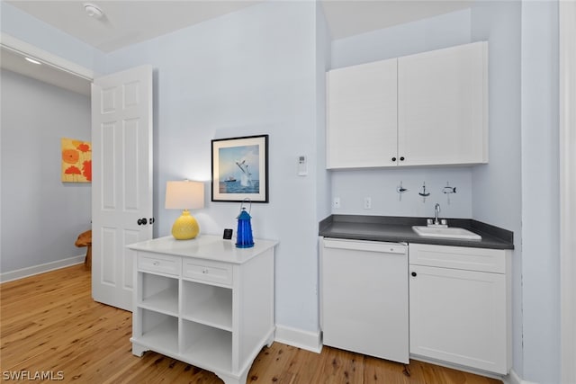 kitchen featuring white cabinets, white dishwasher, sink, and light wood-type flooring