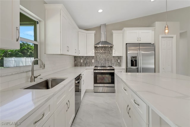 kitchen featuring appliances with stainless steel finishes, pendant lighting, sink, white cabinets, and wall chimney exhaust hood