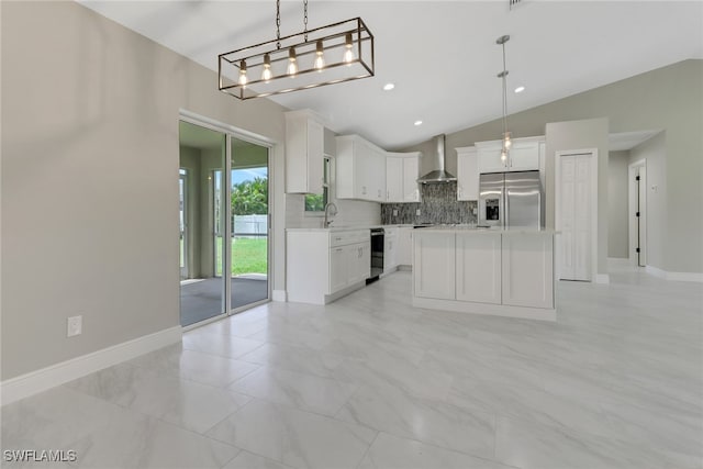 kitchen featuring wall chimney range hood, lofted ceiling, white cabinetry, stainless steel refrigerator with ice dispenser, and a center island