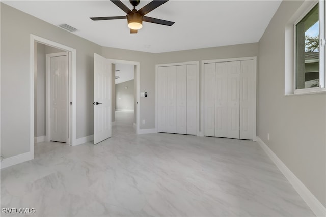 unfurnished bedroom with two closets and ceiling fan