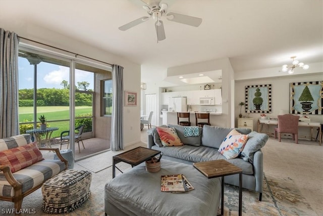 carpeted living room featuring ceiling fan with notable chandelier