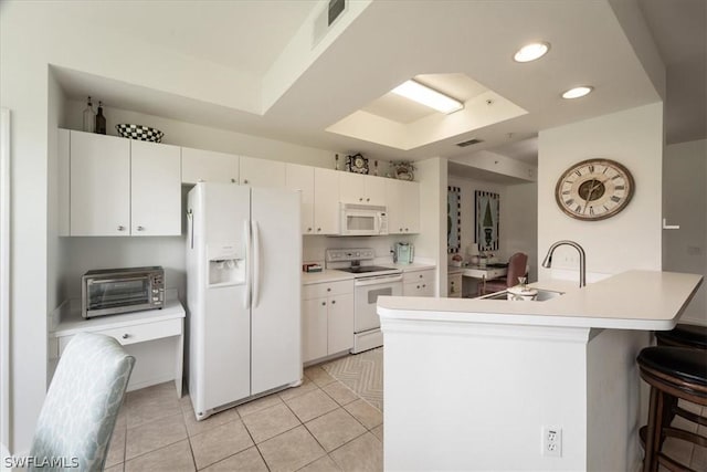 kitchen with light tile patterned floors, white appliances, sink, white cabinets, and a raised ceiling