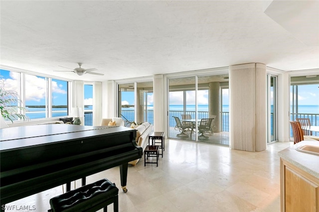 miscellaneous room with plenty of natural light, a water view, ceiling fan, and light tile floors