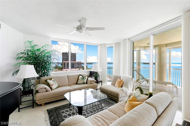 living room featuring ceiling fan and a water view