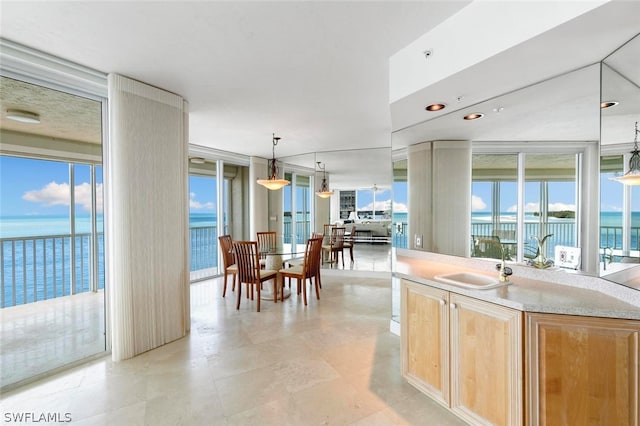 kitchen featuring a wealth of natural light, pendant lighting, sink, and a water view