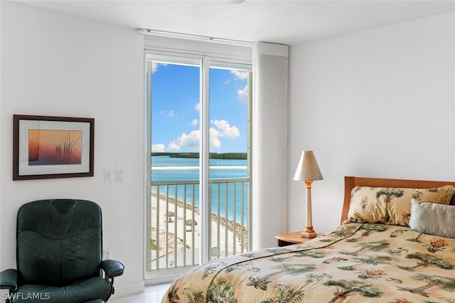 bedroom with multiple windows, a water view, and access to outside