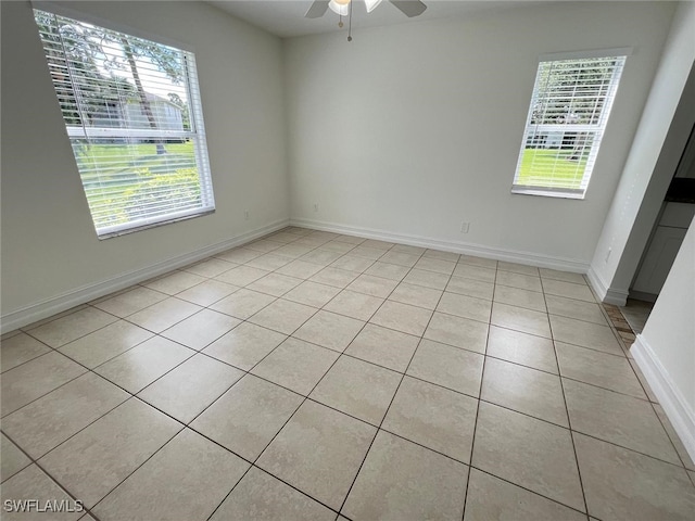 tiled spare room featuring ceiling fan and a healthy amount of sunlight